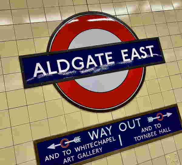 Foto: Das Schild einer U-Bahnstation: Aldgate East mit Wegweisern darunter.