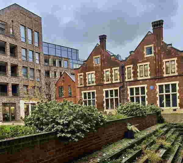 Foto: Ein altes Backsteinhaus neben modernen Häusern.