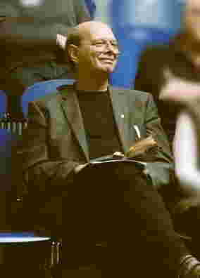 Foto: Ein lächelnder Mann mit Brille und Notizbuch sitzt im Publikum.